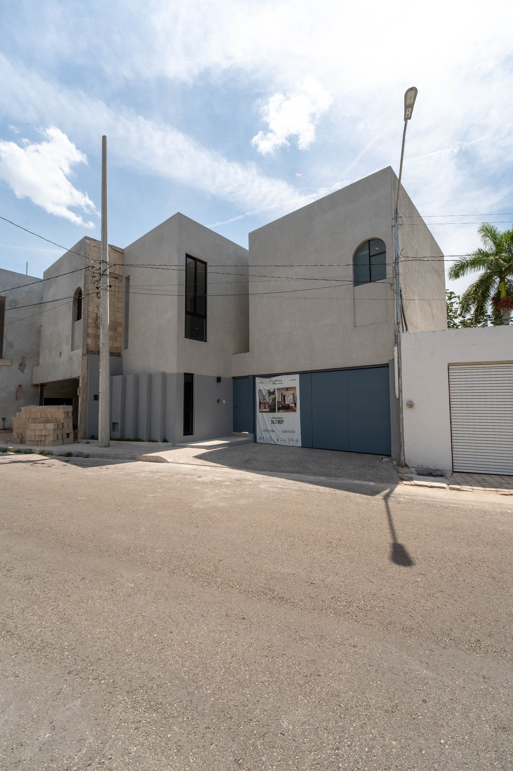Vista exterior de una casa moderna de dos pisos con garaje y un cartel de venta.